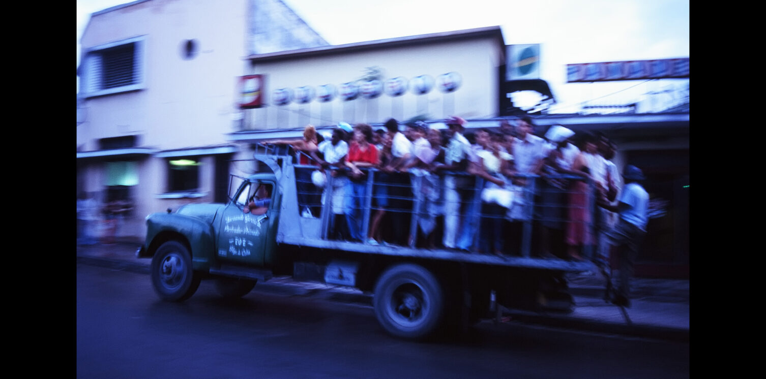 Photo of a bus (formerly a military truck) running through the city of Santiago de Cuba, Cuba